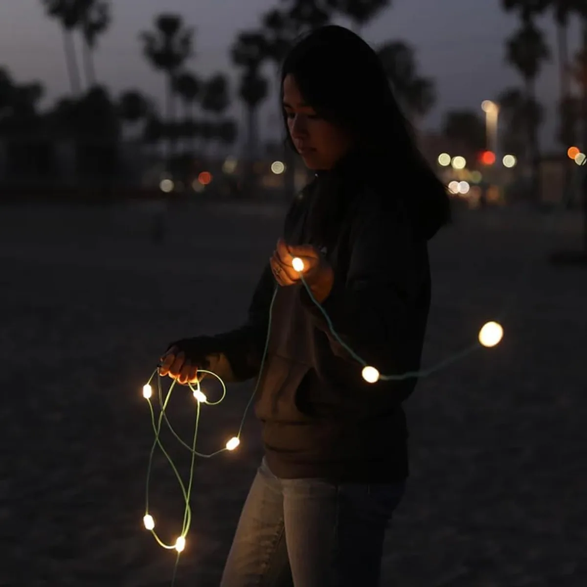 A person arranging illuminated Luci solar string lights at camp