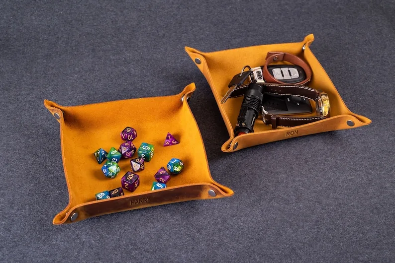 Two personalized leather catchall trays holding keys, a watch, and other small everyday items