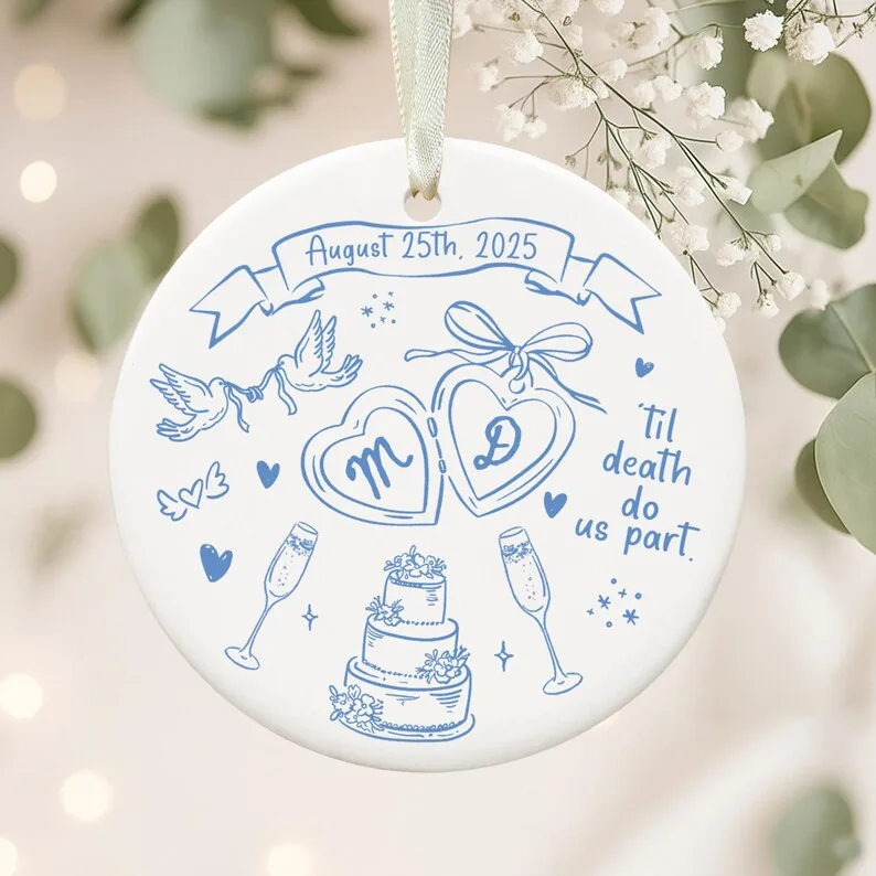 A round personalized ceramic wedding ornament with a date, initials, rings, and cake illustration