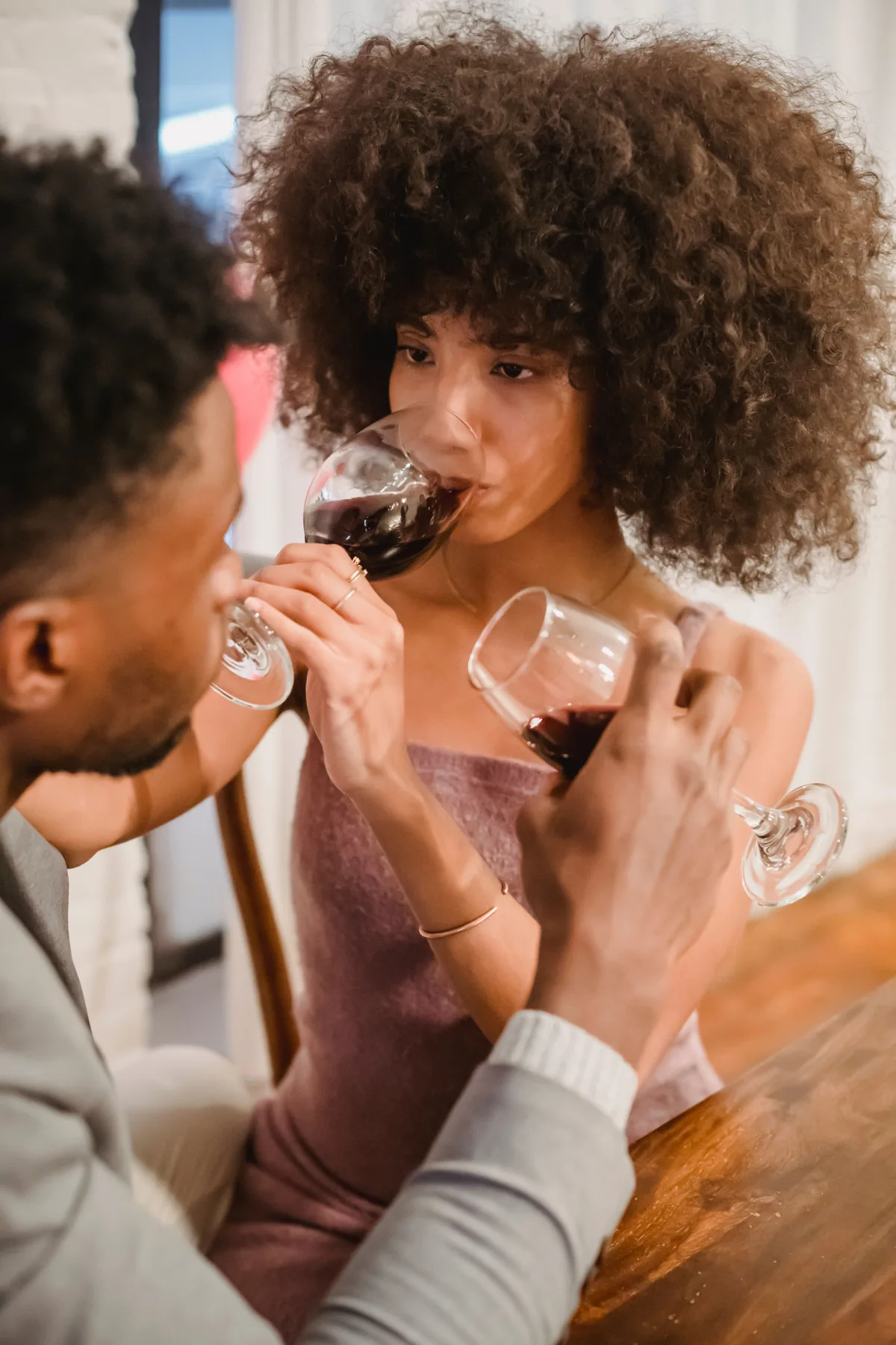 A couple sharing red wine together at a dinner table