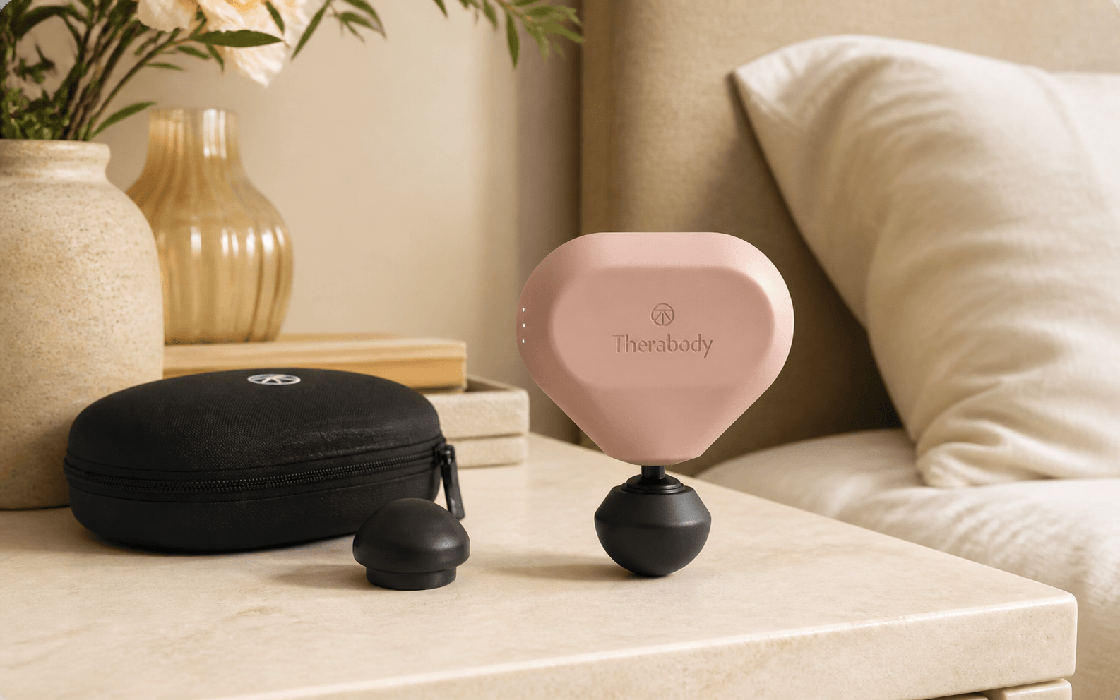 Product-led scene of a Desert Rose Theragun Mini 3 with its travel case and spare attachment